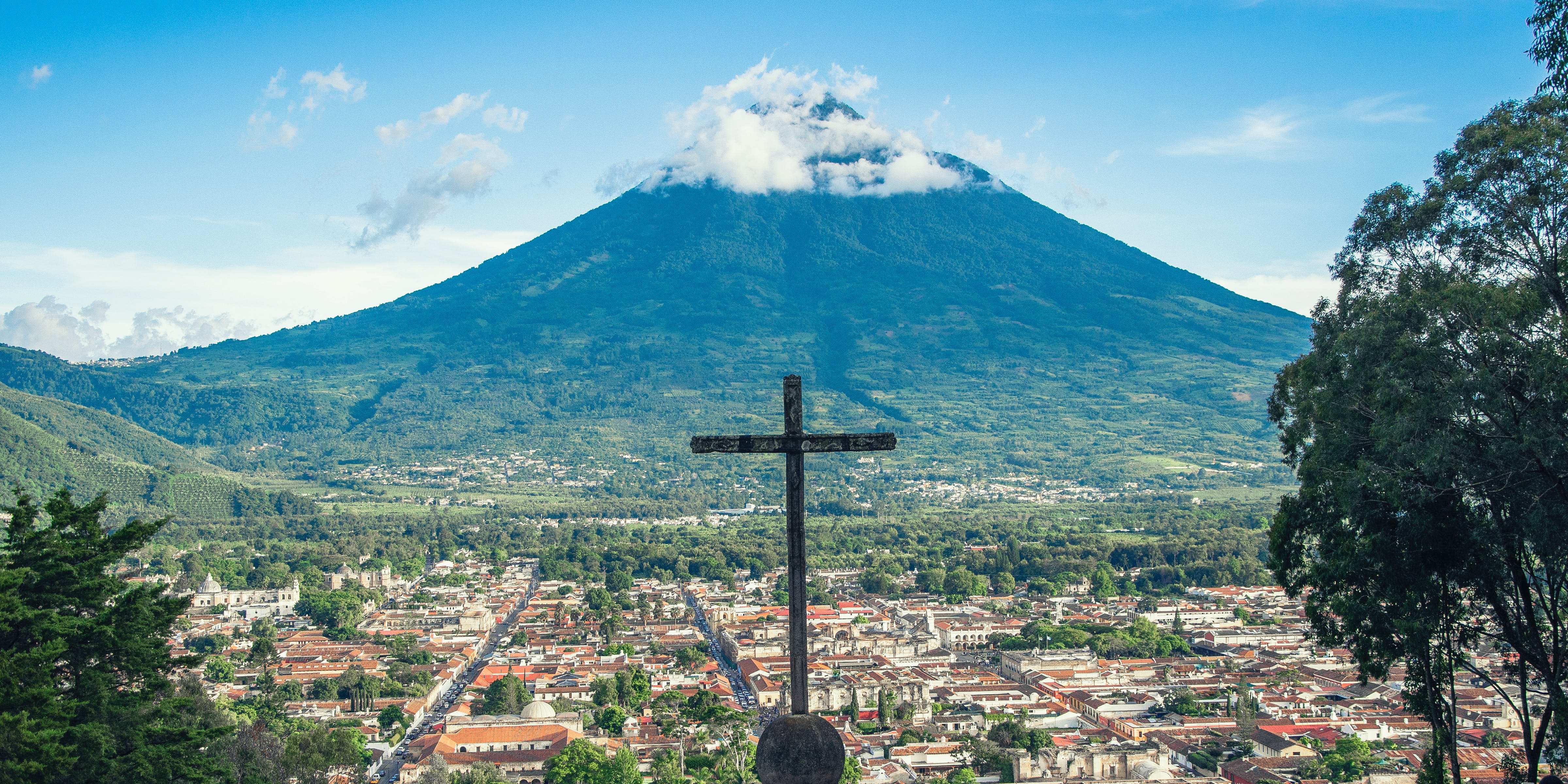 A cross standing above a valley and a volcano in Guatemala