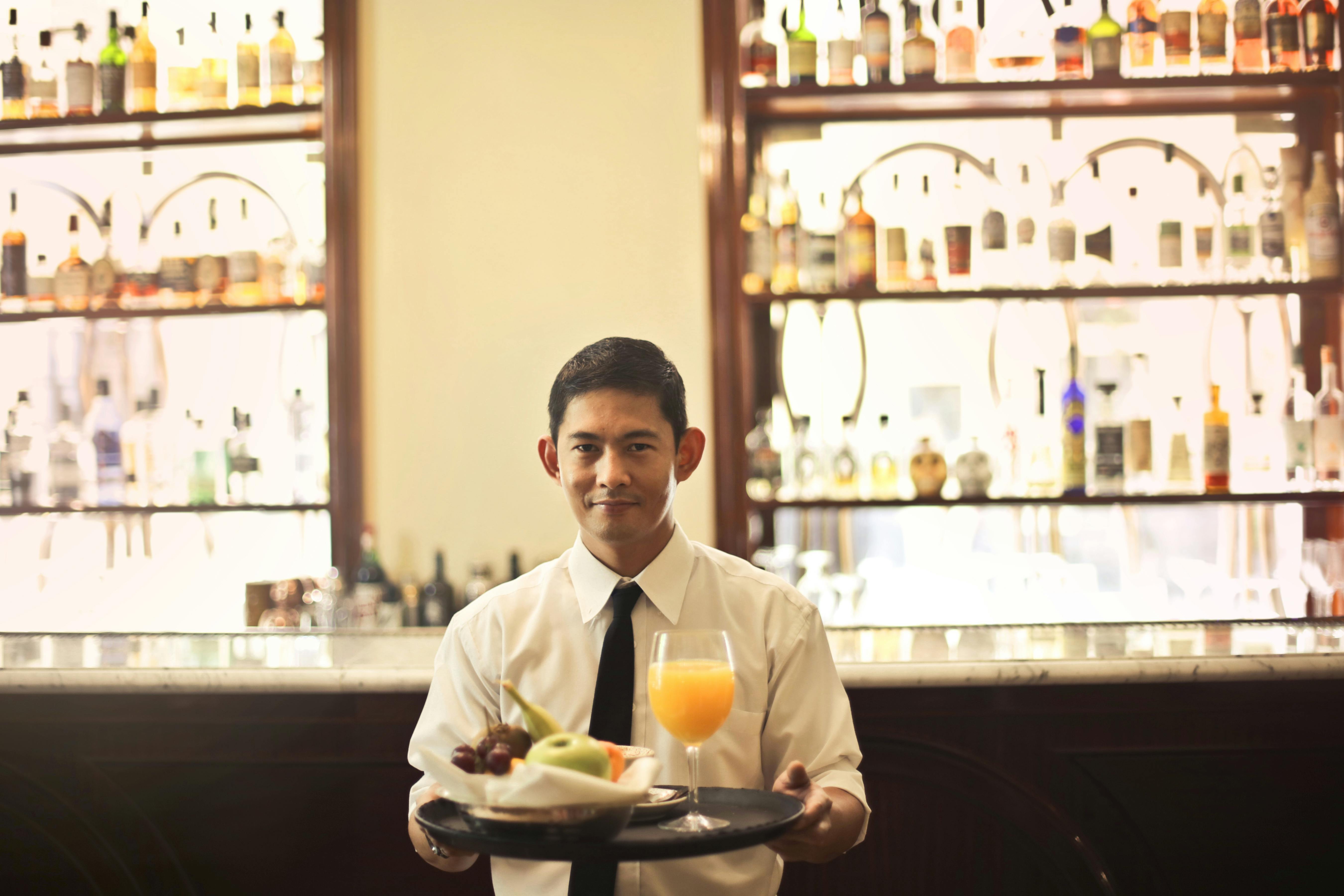 A waiter approaches with drinks on a platter