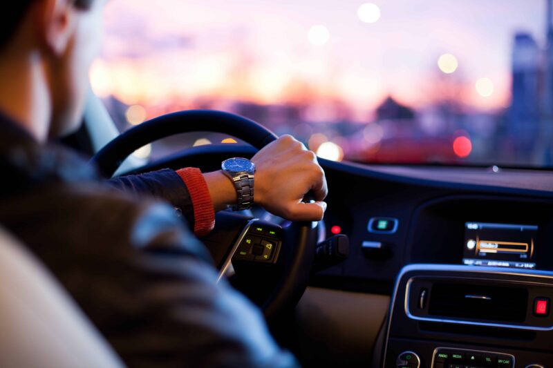 man driving a car with city lights in the window