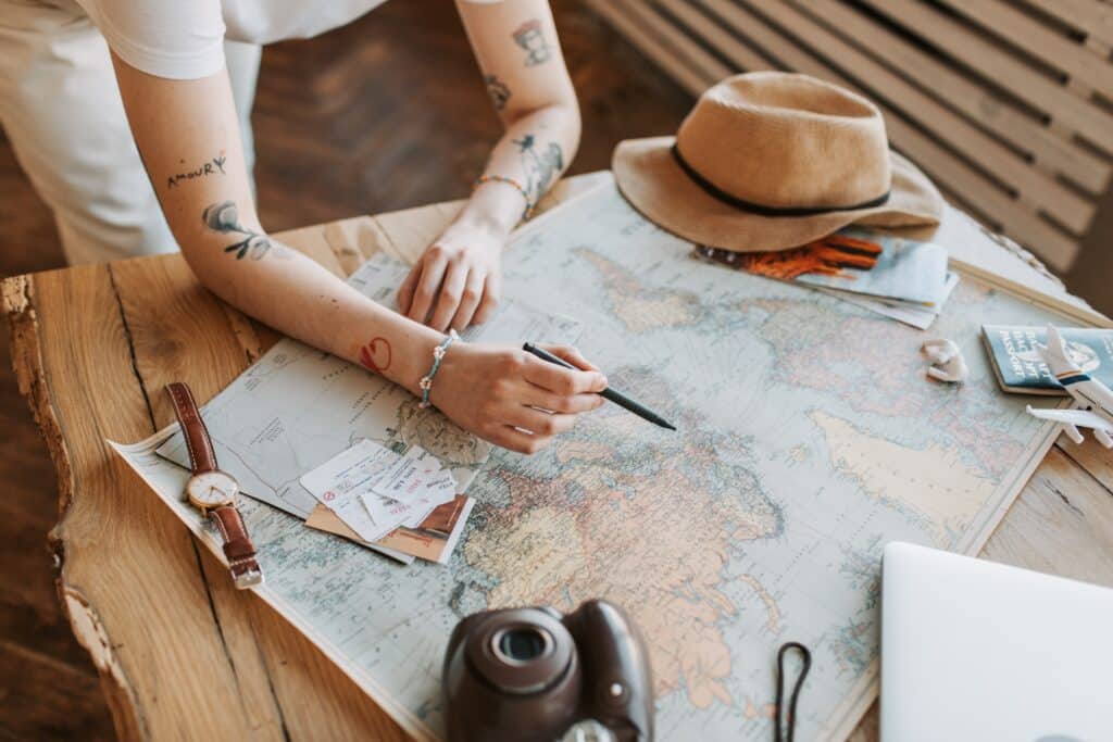 person-looking-over-a-map-with-travel-objects-around-it