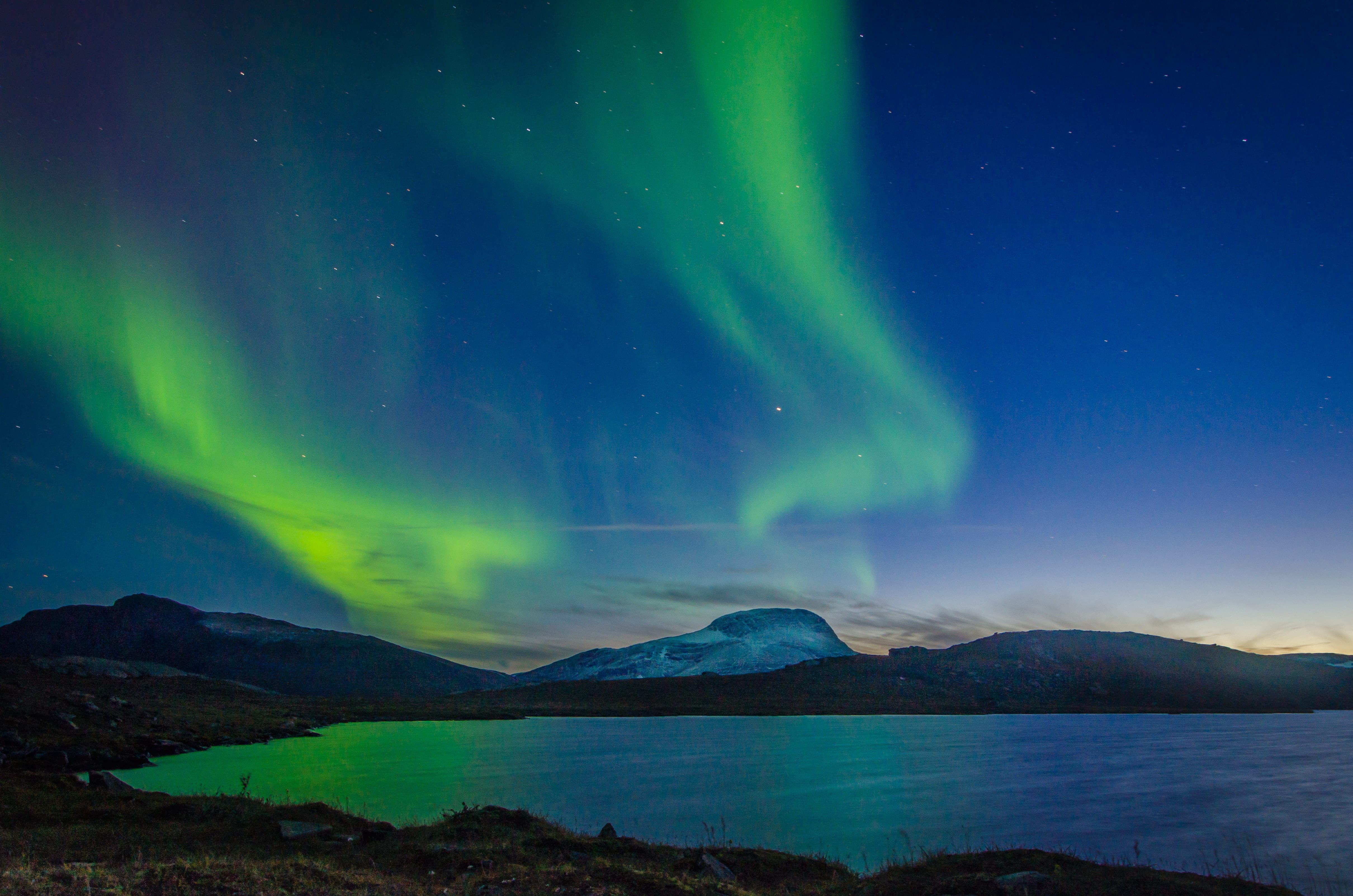 the northern lights over mountains and a lake in Sweden
