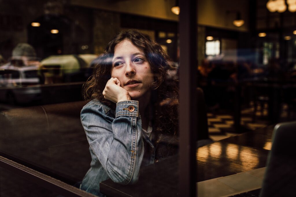 woman-waiting-inside-cafe-and-looking-through-a-window