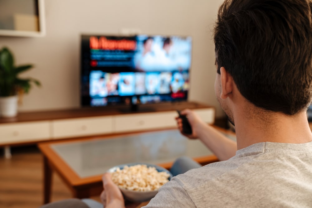 Man-watching-TV-and-eating-popcorn-at-home