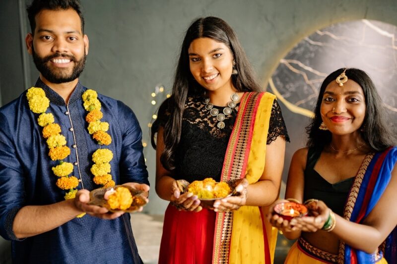 three-people-from-india-in-traditional-clothing-holding-marigolds
