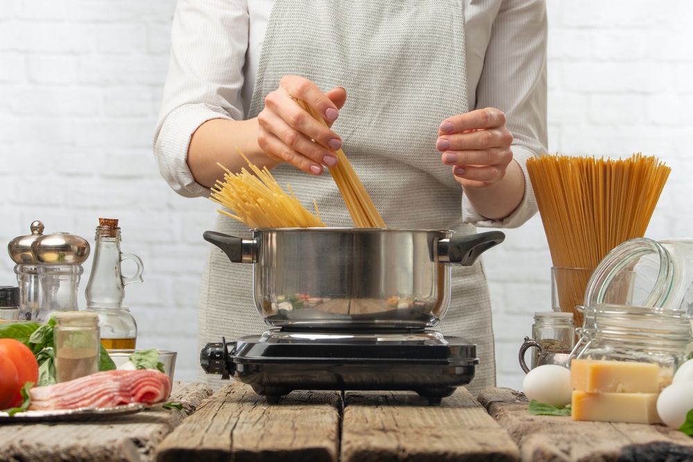 woman in apron making spaghetti