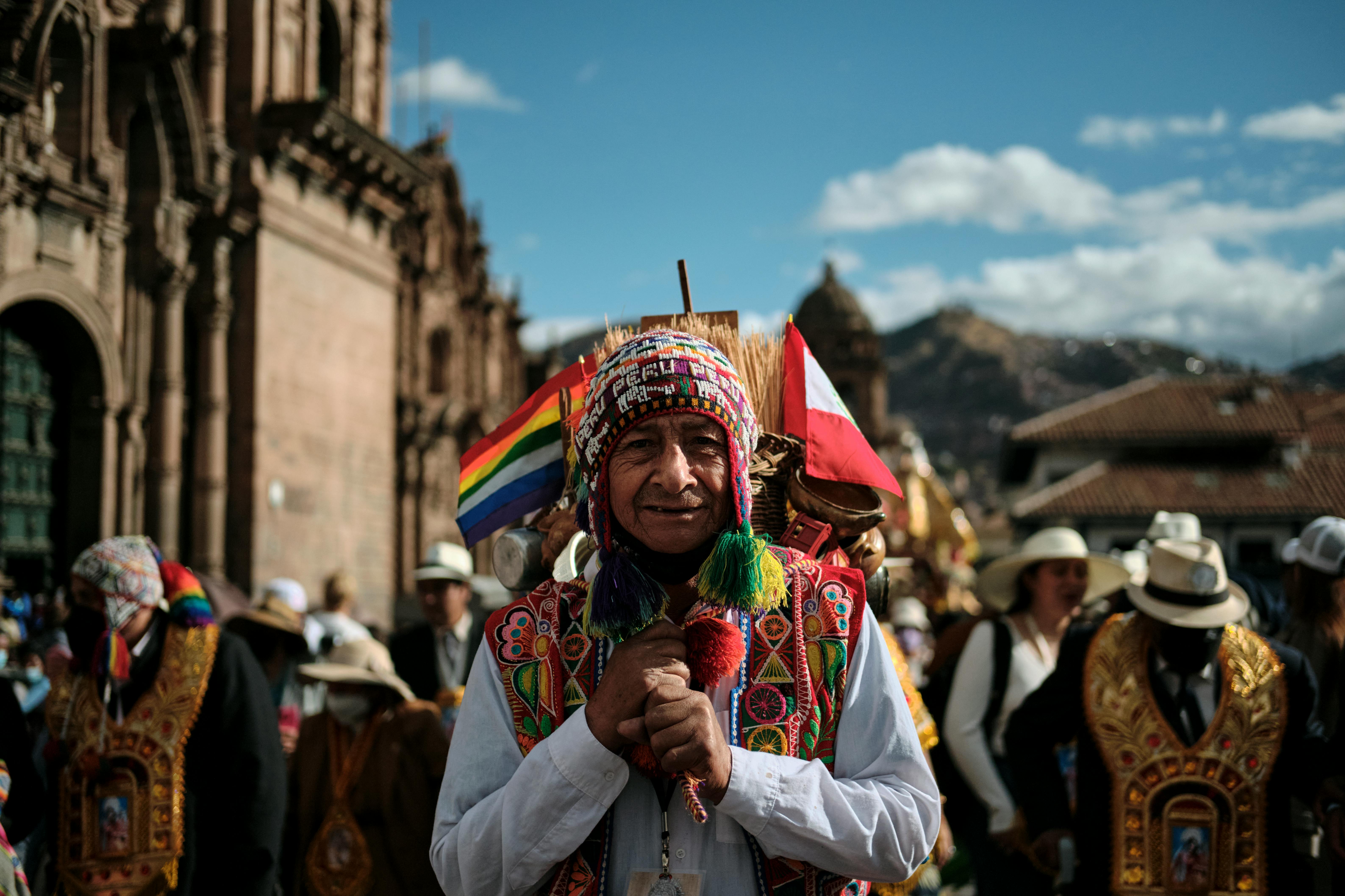 A man in Andean indigenous dress stands in the road