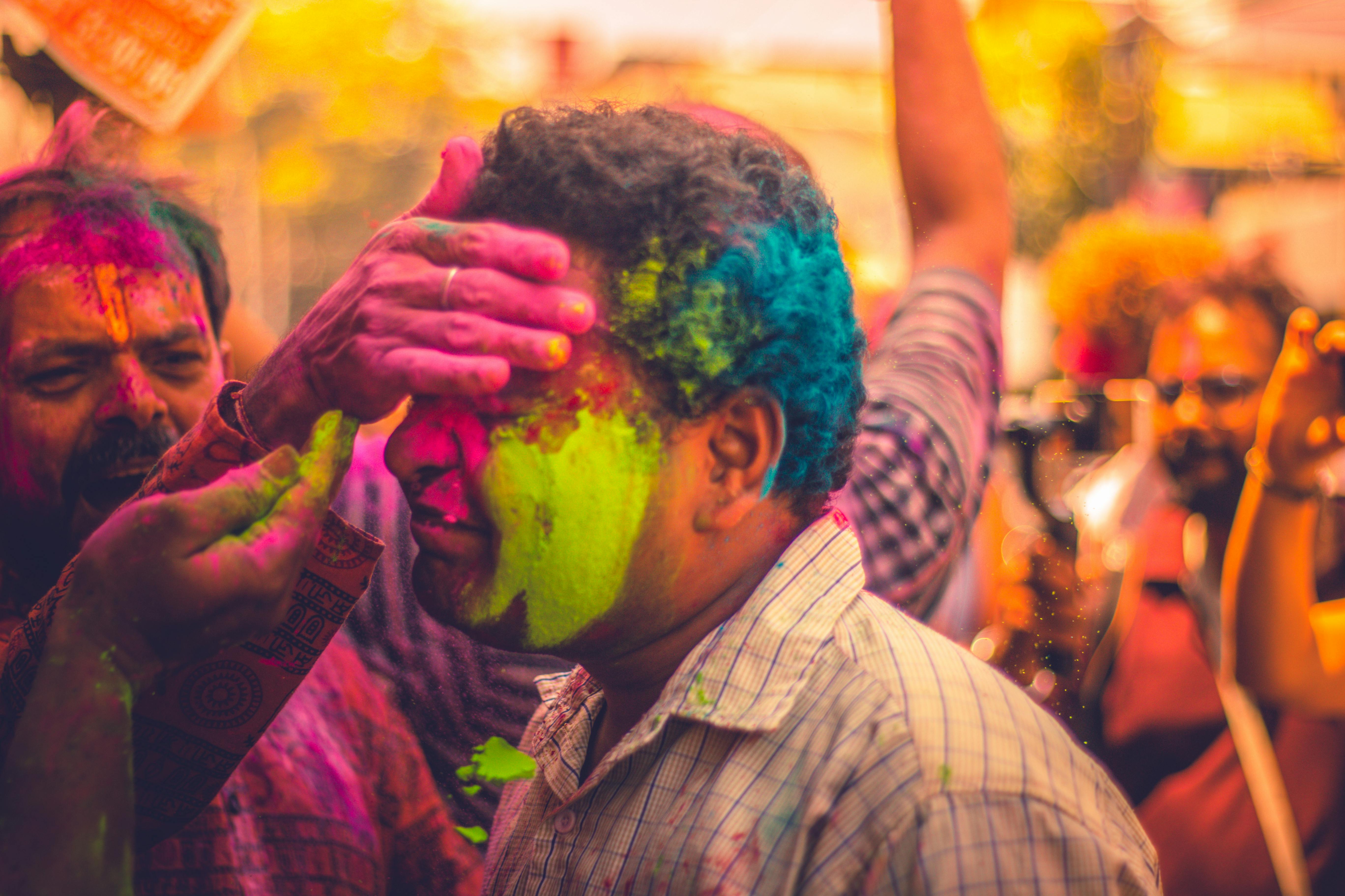 A man being covered in brightly dyed powder at an Indian holi festival