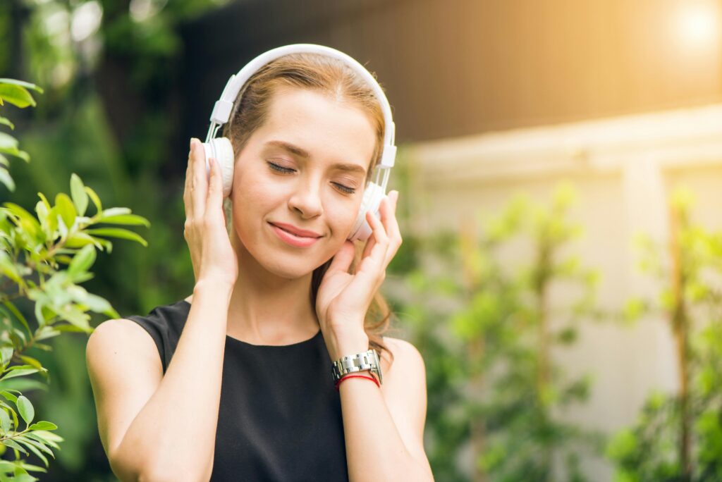 A young woman listens to Spotify on headphones outside